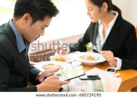 Asian business break for lunch at a restaurant.He was watching the stock market at the table.