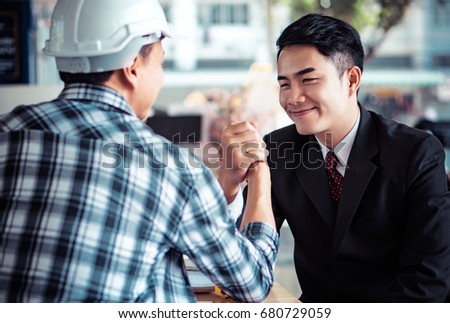 Asian businessman arm wrestle challenge with engineer, business abstract concept.