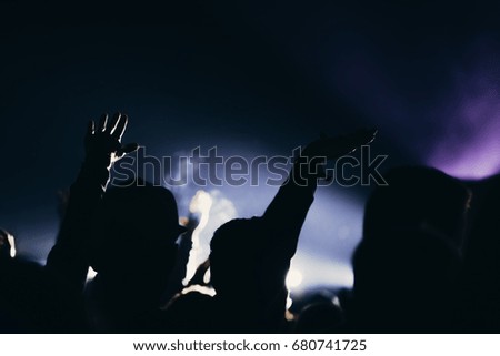 Stage lights and crowd of audience with hands raised at a summer music festival.