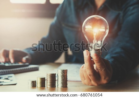 business accounting with saving money with hand holding lightbulb concept financial background Royalty-Free Stock Photo #680761054