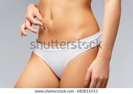 Beautiful Slim Woman In Perfect Body Shape. Closeup Healthy Female With Soft Skin, Fit Flat Belly In Bikini Panties Holding Skin With Fingers, Measuring Fat. Weight Loss Diet Concept. High Resolution