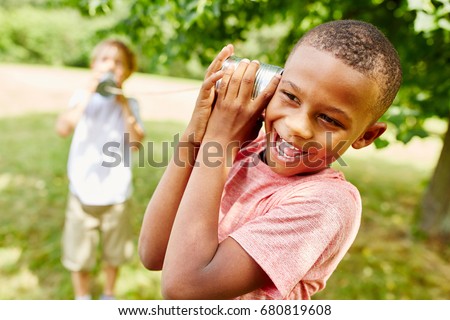 African child calling friend with tin can telephone  Royalty-Free Stock Photo #680819608