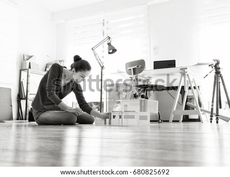 View from the ground. A woman architect working on a construction project at office. She sits on the floor and finalizes a model house. Black and white picture