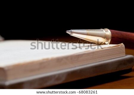 Classy pen lying on a notebook against a black background Royalty-Free Stock Photo #68083261