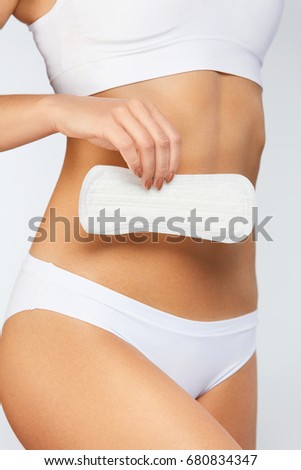 Female Hygiene. Closeup Of Beautiful Woman With Fit Slim Body In White Underwear Holding Sanitary Towel, Panty Liner In Hands. Girl Holding Clean Period Pad, Feminine Intimate Product. High Resolution