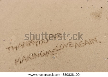 Handwriting  words "THANK YOU FOR MAKING ME LOVE AGAIN." on sand of beach.