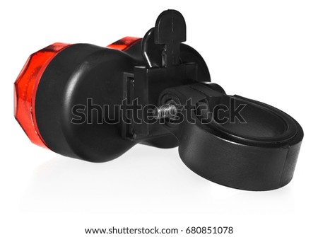 Rear bike lamp. Lighting in red color. Bicycle mounting black plastic. Equipment on a white background with a slight reflection.