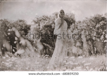 Vintage black and white photo of smiling bride in meadow with flowers