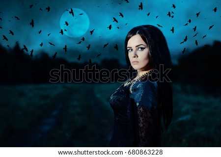 A young witch on background of a full moon and a flock of crows. Portrait of a attractive woman in a black dress in a low key. Fantasy illustration. Fairy tale