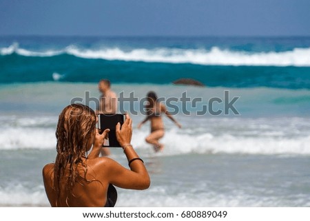Tourist girl taking people photo which playing in water