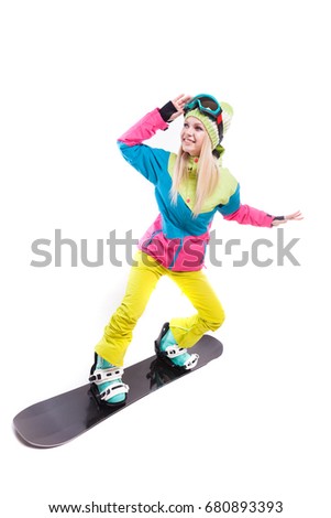 vertical picture, isolated on white, pretty young caucasian girl in colorful ski costume, yellow trousers, blue snow boots and blue ski glasses riding on black snowboard, hand on glasses