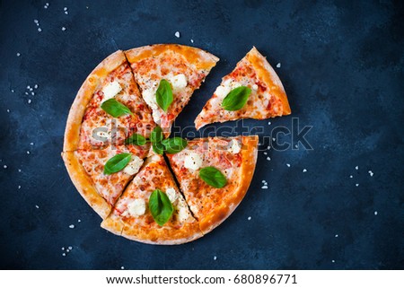 Pizza "Four cheeses" with tomato sauce, olives,  fresh mozzarella, parmesan and basil on the dark concrete background