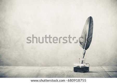 Quill pen with inkwell  on wooden desk. Vintage old style sepia photography Royalty-Free Stock Photo #680918755