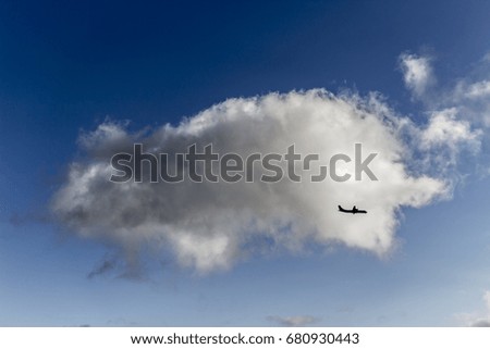 Silhouette of and airplane crossing an isolated cloud