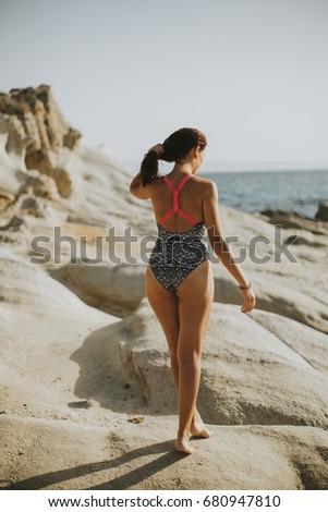 Pretty young woman on the stony beach at sunny day
