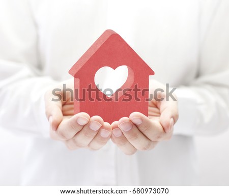 Small red house with heart in hands 