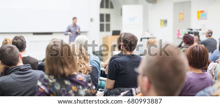 Male speaker giving presentation in lecture hall at university workshop. Audience in conference hall. Rear view of unrecognized participant in audience. Scientific conference event. Royalty-Free Stock Photo #680993887