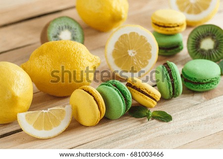 Green and yellow french macarons with kiwi, lemon and mint decorations, soft focus background