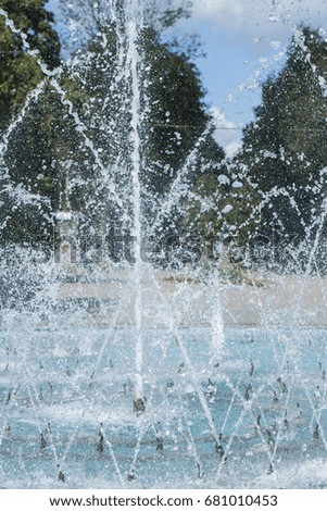 Fountain and water splashes against the trees, vertical frame