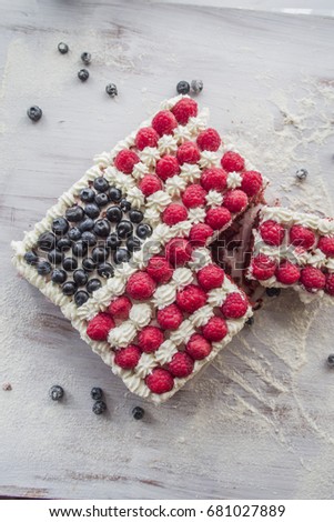 American flag is reproduced in a a cake with raspberry ,whipped cream and blueberry, over a white background, " happy 4th july" text over plain wheatmeal