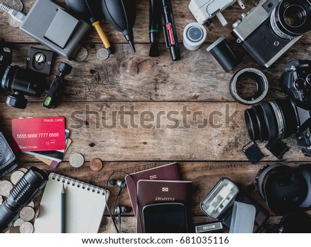 tourism concept, travel concept with vintage camera, passport, credit card, universal plug, notebook, smartphone and traveler accessories on wooden background with white paper for copy space text