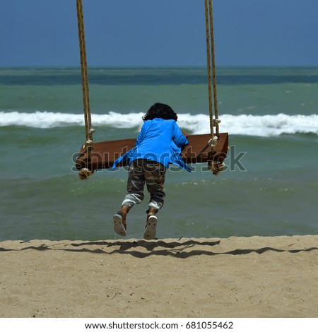boys alone  playing on the swings by the beach,selective focus.