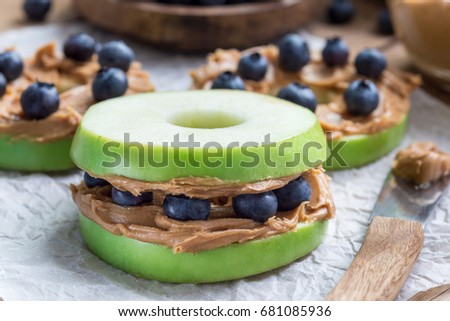 Healthy sandwich. Green apple rounds with peanut butter and and blueberries on wooden table, horizontal Royalty-Free Stock Photo #681085936