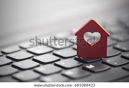 Small red house with heart over laptop keyboard 