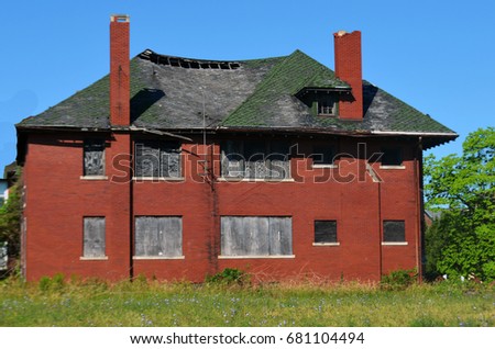 An abandoned and boarded up brick building surrounded by weeds  in Detroit, MI