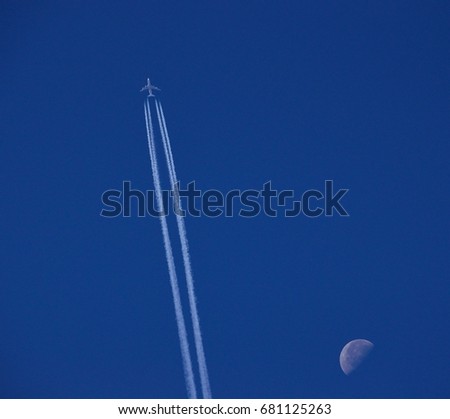 Awesome blue sky, modern airplane at high altitude and the waning moon