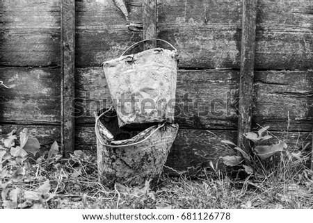 Old buckets stained in cement on a wooden background, black and white photo