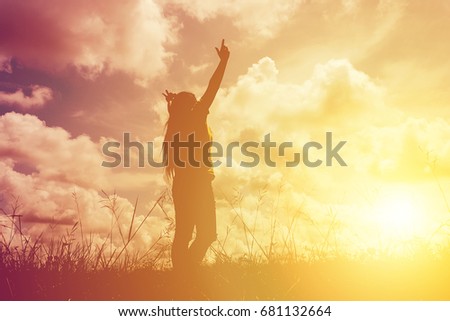 Silhouette young woman with raised hands standing on meadow on sunset, Sunset light effect, Freedom concept