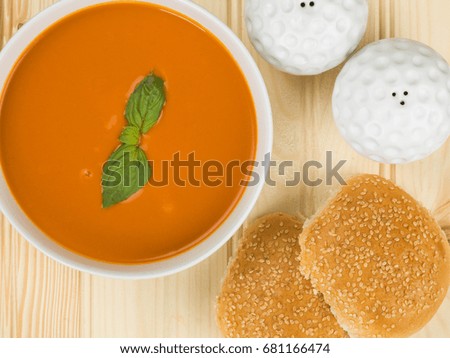 Bowl of Tomato and Basil Soup Against a Natural Wooden Background