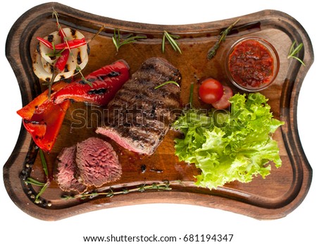 Juicy steak fillet mignon made from marbled beef with baked vegetables on a wooden board. Sliced. Isolated