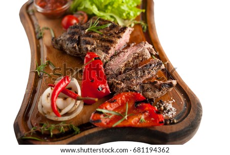 Juicy steak fillet mignon made from marbled beef with baked vegetables on a wooden board. Sliced. Isolated