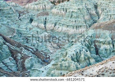Sunset surrealistic landscape in John Day Fossil Beds National Monument Blue Basin area with grey-blue badlands. A branched ravine and Heavily eroded formations.