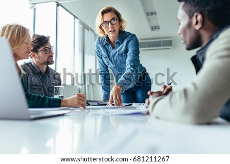 Businesswoman standing and leading business presentation. Female executive putting her ideas during presentation in conference room. Royalty-Free Stock Photo #681211267