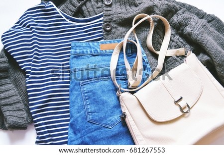 Autumn and winter fashion blogger's outfit. Striped tshirt, brown wool knitted cardigan, blue jeans from denim and beige bag. Casual style, trendy wear. Comfy women's clothing. Flat lay stock photo