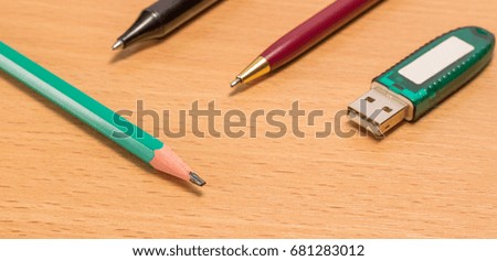 Four objects for information transfer pencil, pen and flash drive on a wooden background