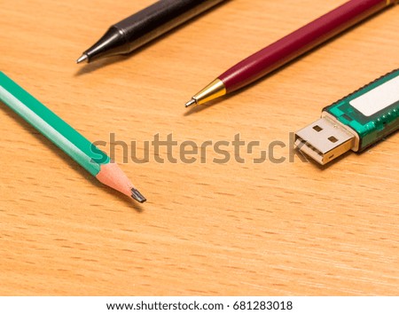 Pencil pens and a flash drive on a wooden background objects for transferring information in various ways