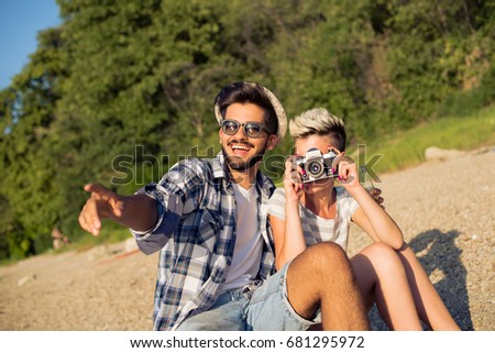 Young man and woman are taking pictures on beach