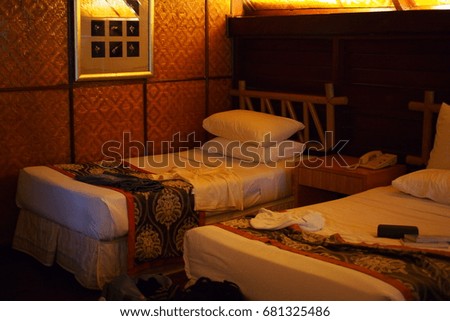 Guests' stuffs on a bed after check-in in the wooden bed room decorated with picture frame.