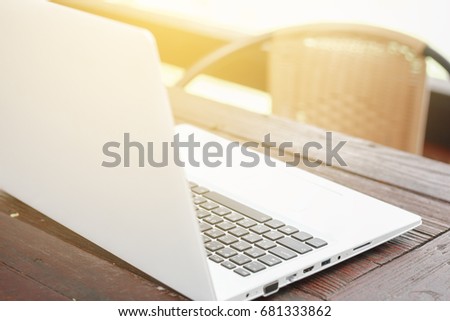 Computer laptop with blank back screen on wooden table with green garden nature background