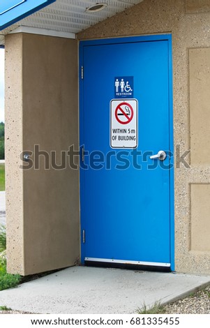 The door to a multisex restroom with a no smoking sign.