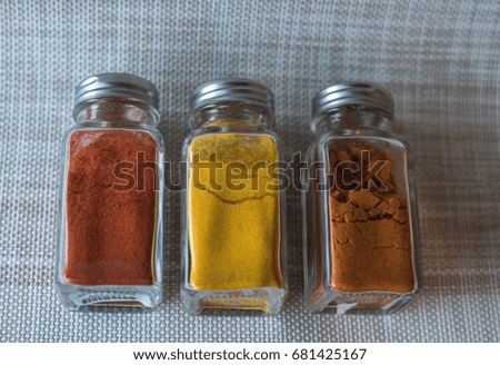 A turmeric powder, curry powder,r and red peper powder in glass bottle in vintage style picture.