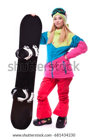 vertical picture, isolated on white, attractive  young caucasian girl in colorful ski suit, red trousers and blue ski glasses, hold black snowboard, hand on waist