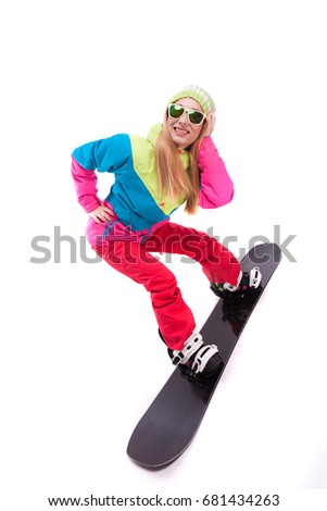 vertical picture, isolated on white, attractive young caucasian girl in colorful ski suit, red trousers and sunglasses ride on black snowboard
