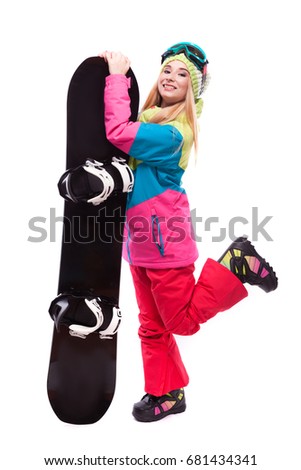 vertical picture, isolated on white, attractive young caucasian girl in colorful ski suit, red trousers and blue ski glasses, hold black snowboard, turned girl, one leg up