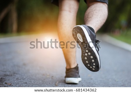 Starting day from morning jog. Full length rear view of young man in sports clothing jogging in park.Man in jogging shoes ready for a run outside at sunset