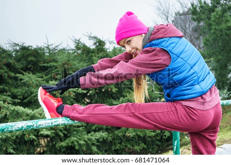 Outdoor sport exercises, sporty outfit ideas. Woman wearing warm sportswear training exercising, stretching legs outside during autumn.